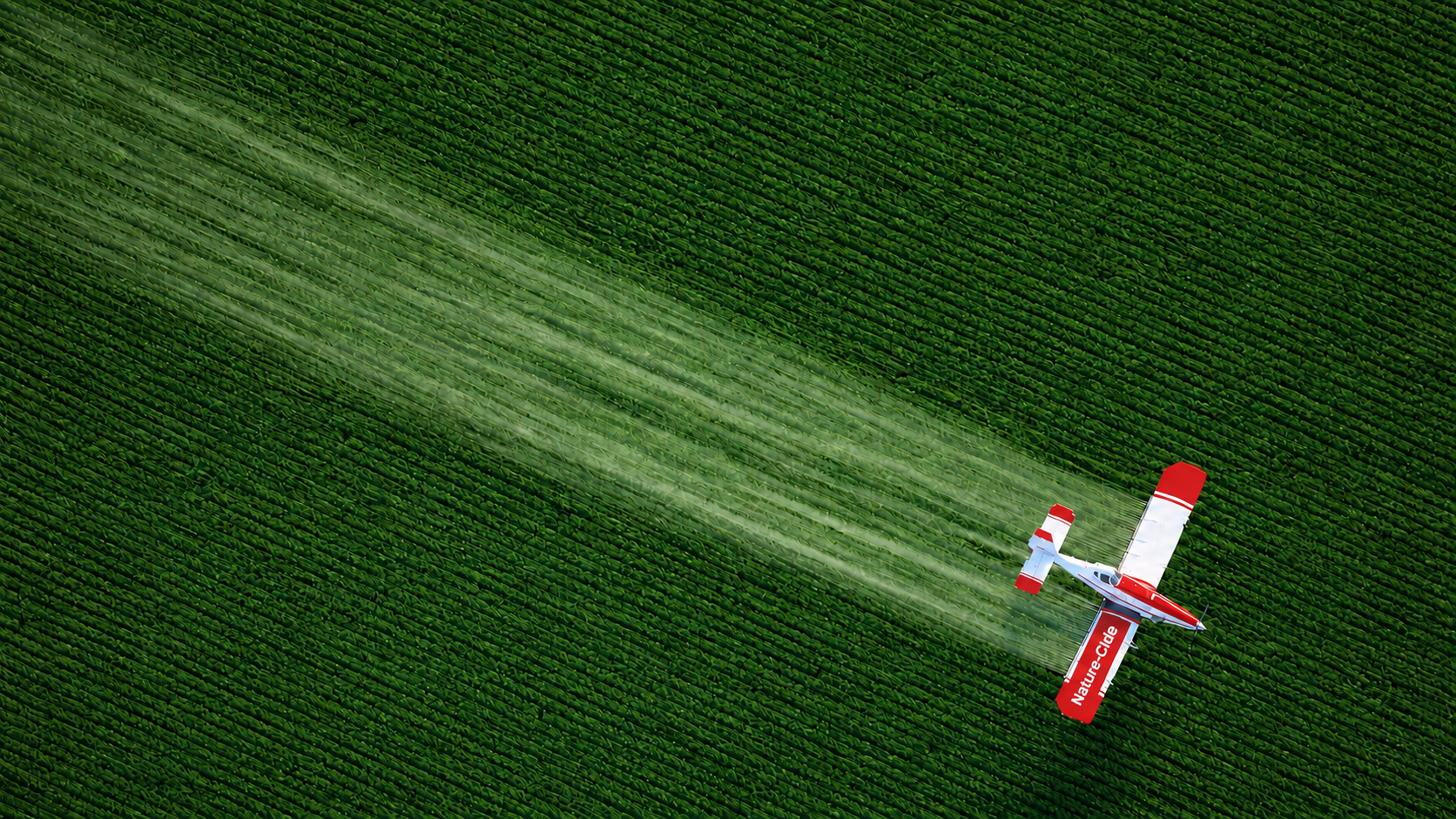 Nature-Cide-branded agricultural aircraft applying treatment over cultivated fields